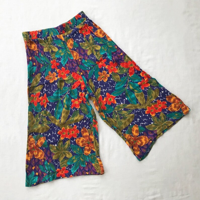 May include: Floral print wide-leg culottes in a vibrant color palette of orange, red, green, blue, and purple. The fabric has a crinkled texture.