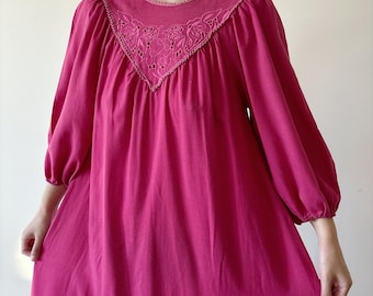 Könnte beinhalten: Ein rosafarbenes, langärmeliges Kleid mit einem weißen Spitzenausschnitt. Das Kleid hat eine lockere, fließende Passform und ist aus einem weichen, bequemen Stoff gefertigt.