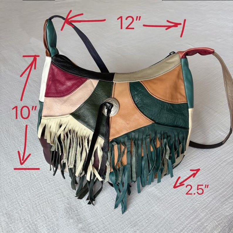 May include: A patchwork leather shoulder bag with a 10-inch height and 12-inch width. The bag features a variety of colors, including green, tan, burgundy, and black, with a fringe detail at the bottom. A silver-tone metal button adorns the front.