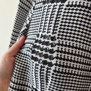 May include: Black and white patterned fabric with a black sequin design. The fabric has a geometric pattern.