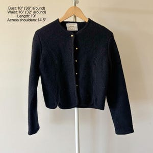 Puede incluir: Chaqueta de lana negra con cuello redondo y mangas largas. La chaqueta tiene botones dorados y un dobladillo festoneado. Medidas: Contorno de pecho 45,7 cm (91,4 cm), Cintura 40,6 cm (81,3 cm), Largo 48,3 cm, Ancho de hombros 36,8 cm.