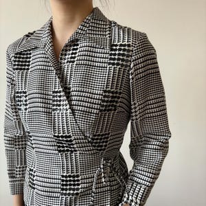 May include: A black and white checkered wrap dress with a long sleeve and a tie at the waist.