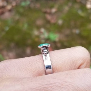 Puede incluir: Un anillo de plata con una piedra preciosa verde y una peque&ntilde;a bola de plata en la banda.