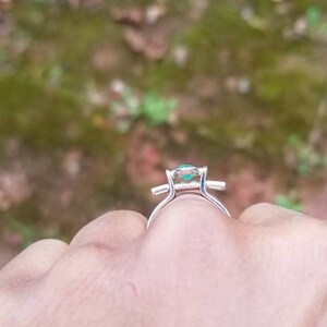 Puede incluir: Un anillo de plata con una piedra preciosa verde engastada en forma cuadrada.