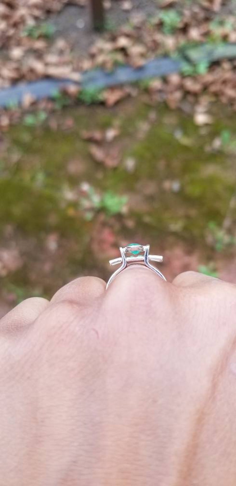 Puede incluir: Un anillo de plata con una piedra preciosa verde engastada en forma cuadrada.