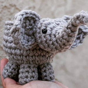Puede incluir: Un juguete de elefante de crochet gris con una superficie texturizada. El elefante tiene una trompa larga y orejas grandes.