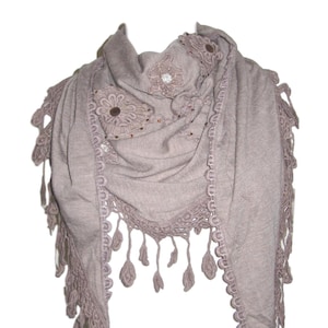 May include: A taupe-colored scarf with intricate floral embroidery and delicate lace trim. The scarf features a triangular shape with scalloped edges and dangling leaf-shaped tassels. The design includes small, sparkling embellishments.
