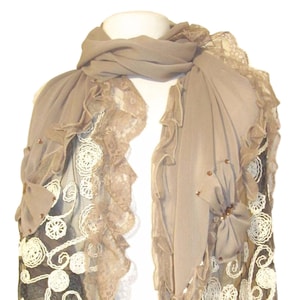 May include: A brown and beige scarf with lace trim and embellishments. The scarf is made of a sheer fabric and has a delicate, feminine look.