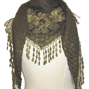 Może przedstawiać: Brązowy dzianinowy szal z koronkową lamówką w kolorze złotym i dużym złotym zdobieniem kwiatowym.