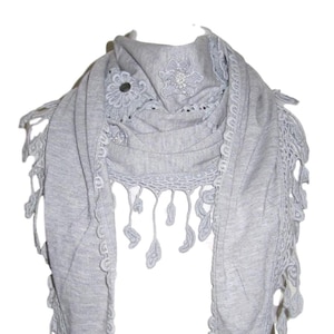 May include: A gray scarf with a crocheted trim and floral embellishments.