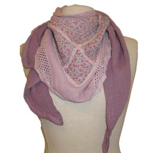 Könnte beinhalten: Ein mauvefarbener Schal mit Blumendruck und Spitzenbesatz. Der Schal ist gefaltet und über eine Schaufensterpuppe gelegt.