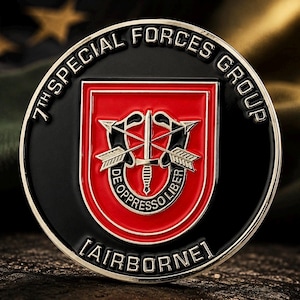 Könnte beinhalten: Eine kreisförmige Challenge Coin mit schwarzem Rand und der Aufschrift 7TH SPECIAL FORCES GROUP sowie AIRBORNE. In der Mitte befindet sich ein rotes Wappen mit einem silbernen Dolch und zwei gekreuzten Pfeilen, umgeben vom Schriftzug DE OPPRESSO LIBER.