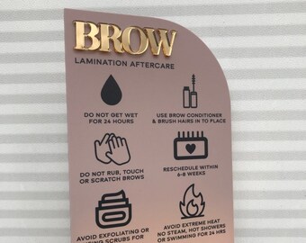 May include: A pink and gold laminated brow aftercare sign with instructions for brow care. The sign includes icons and text such as "Do not get wet for 24 hours", "Use brow conditioner and brush hairs into place", "Do not rub, touch or scratch brows", "Reschedule within 6-8 weeks", "Avoid exfoliating or using scrubs for 3 days", and "Avoid extreme heat, no steam, hot showers or swimming for 24 hours".