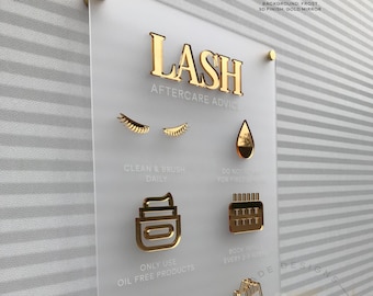 May include: A white acrylic sign with gold lettering and icons outlining lash aftercare advice. The sign reads "LASH AFTERCARE ADVICE" and includes instructions such as "Clean & Brush Daily", "Only Use Oil Free Products", "Book Infills Every 2-3 Weeks", and "No Mascara".