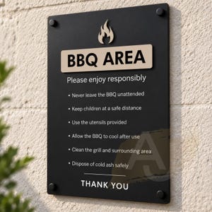 May include: A rectangular black sign with a beige header featuring a flame icon and the text BBQ AREA. Below, white text lists safety rules: Please enjoy responsibly, Never leave the BBQ unattended, Keep children at a safe distance, Use the utensils provided, Allow the BBQ to cool after use, Clean the grill and surrounding area, Dispose of cold ash safely, and THANK YOU.