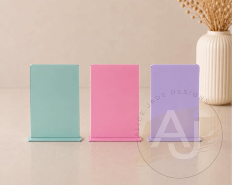 Op de afbeelding: Drie rechthoekige display stands in pastelkleuren: mintgroen, roze en lavendel. De stands hebben een basis en een verticaal paneel. De lavendelkleurige stand heeft de tekst "ALICE JADE DESIGNS" en de letters "AJ".