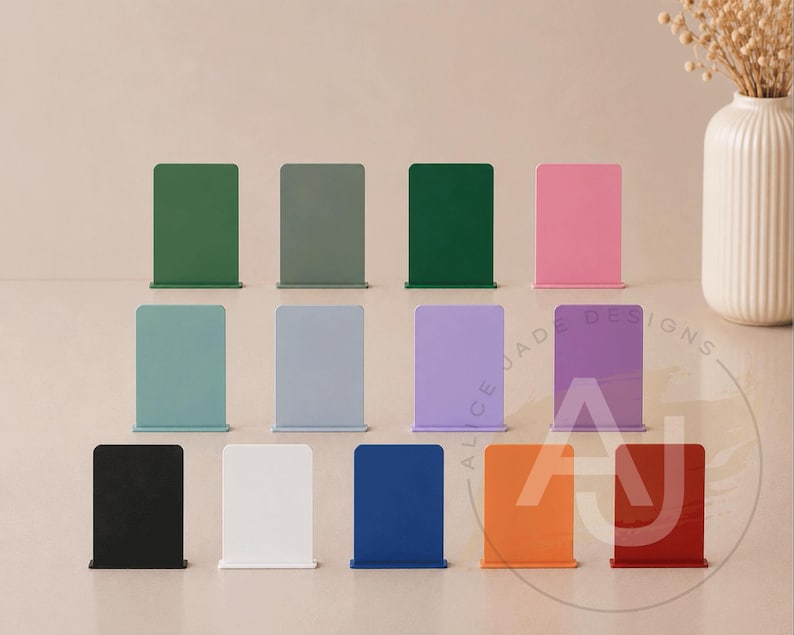 Op de afbeelding: Een verzameling kleurrijke, rechthoekige boekensteunen in verschillende tinten, waaronder groen, roze en blauw. De boekensteunen zijn in rijen gerangschikt en tonen een reeks tinten voor woon- of kantoordecoratie. De boekensteunen zijn van metaal.
