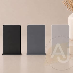 Op de afbeelding: Drie rechthoekige display stands in zwart, grijs en wit. De stands hebben een afgeronde bovenkant en een rechthoekige basis. De witte stand heeft de tekst "CE JADE DESIGNS" en de letter "A" erop.
