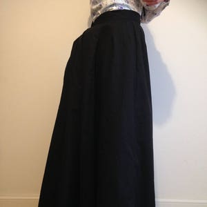 May include: A black maxi skirt with a pleated design. The skirt is made of a smooth, flowing fabric.