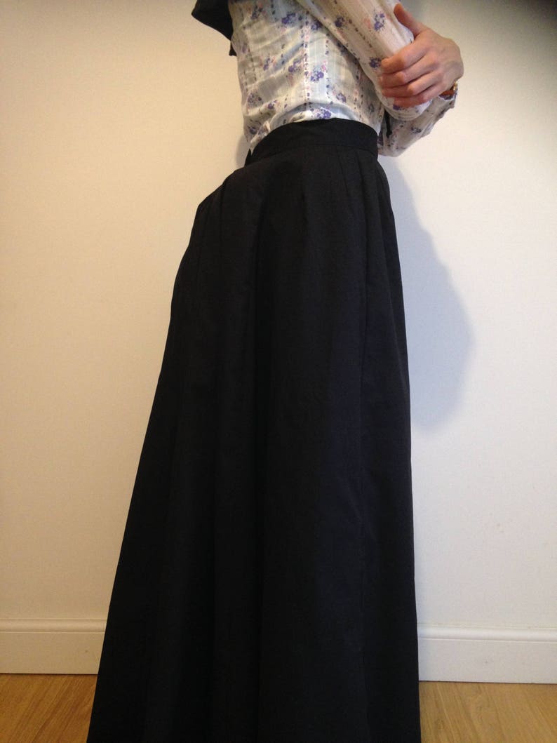 May include: A black maxi skirt with a pleated design. The skirt is made of a smooth, flowing fabric.