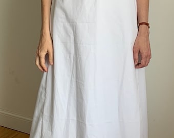 May include: A white, long-sleeved dress with a gathered neckline and puffed sleeves. The dress has a fitted bodice and a flowing skirt.