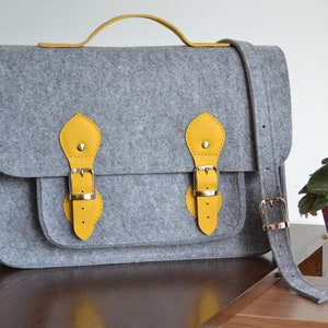 Bolso bandolera de fieltro para portátil: detalles de cuero y correa ajustable.