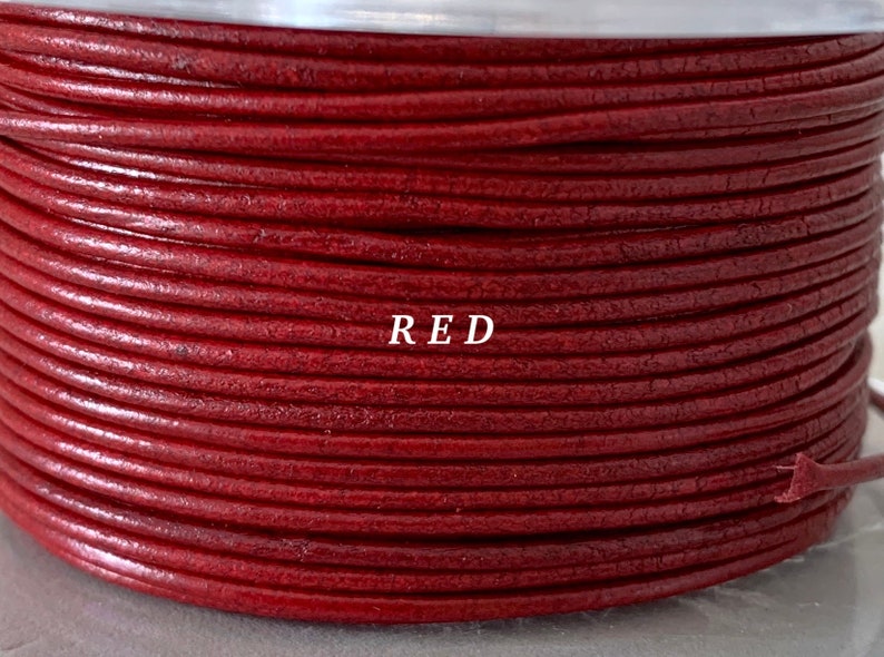 K&ouml;nnte beinhalten: Eine Spule aus rotem Lederband. Das Band ist eng gewickelt und zeigt eine strukturierte Oberfl&auml;che. Das Wort "RED" ist wei&szlig; auf der Spule aufgedruckt. Dieses Band eignet sich f&uuml;r Schmuckherstellung und Basteln.
