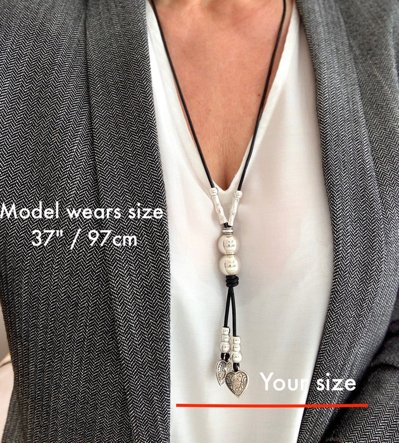 May include: A black leather necklace with silver beads and heart charms. The necklace is 37 inches long. Model wears size 37"/97cm.