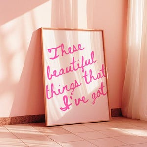 May include: A framed print with a pink background and the text "These beautiful things that I've got" in pink cursive lettering.