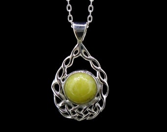 May include: A silver pendant necklace featuring a round, smooth, lime-green stone set within an intricate, openwork silver frame with interwoven knot patterns. The pendant hangs from a simple silver chain against a solid black background.