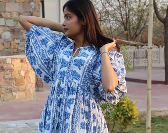 May include: A white maxi dress with a blue floral print and puffed sleeves. The dress has a gathered waist and a V-neckline.
