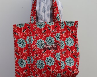 May include: Red and blue floral print tote bag with a quilted design. The bag has two handles and is made of cotton fabric.