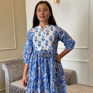 Peut inclure: Une robe à fleurs bleu et blanc avec une jupe à volants et des manches 3/4. La robe a un col en V et un col blanc.