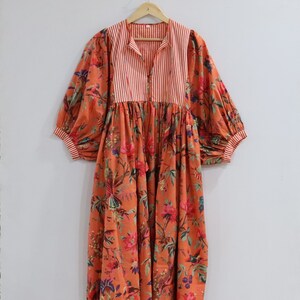 May include: A long, orange dress with a floral print and a striped bodice. The dress has a gathered skirt and puffed sleeves.