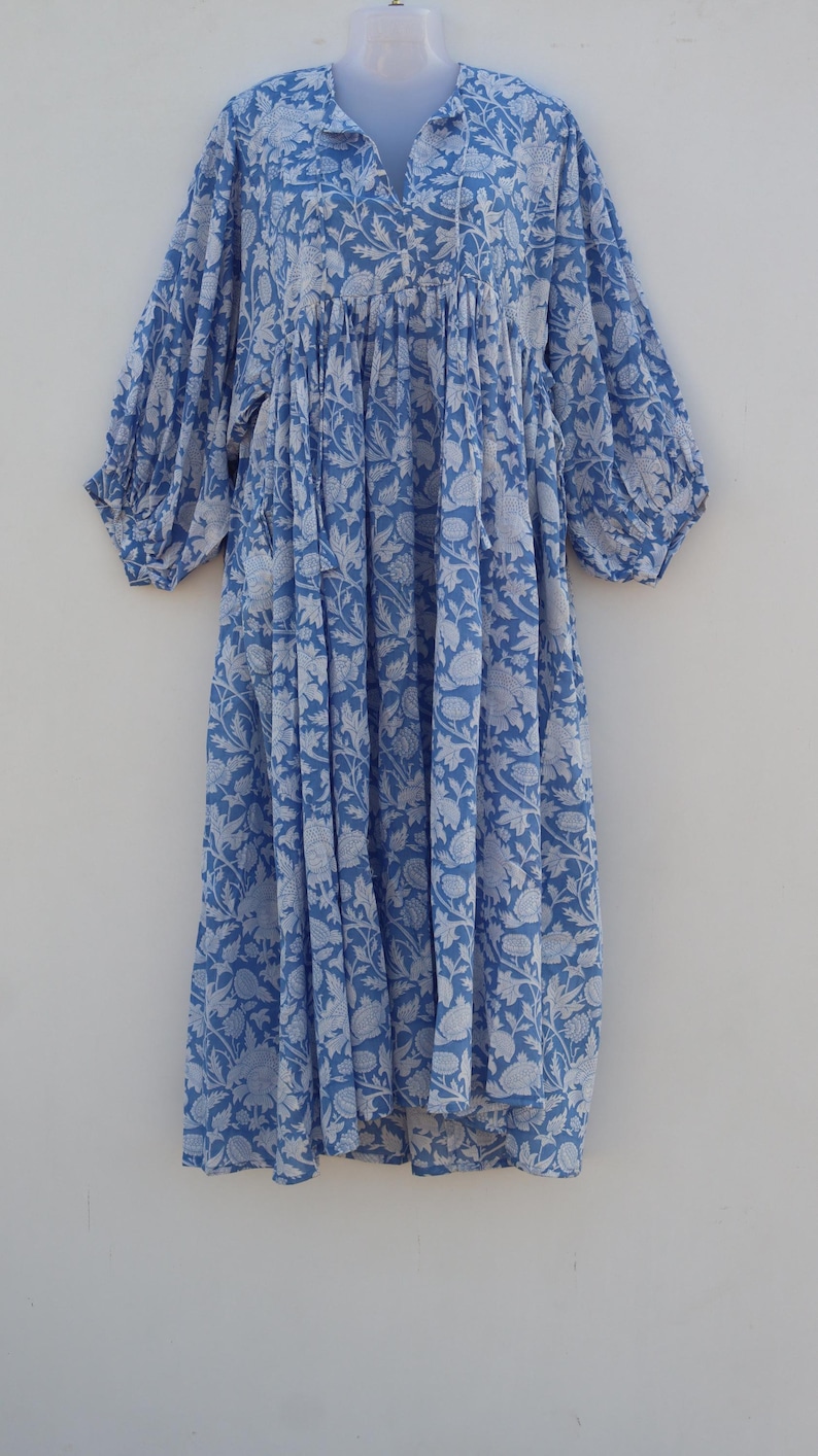 May include: A blue and white floral print dress with a v-neck and 3/4 sleeves. The dress has a loose, flowing fit and is made of a lightweight fabric.