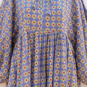 Puede incluir: Un vestido largo de manga larga de color morado con estampado floral rojo y verde. El vestido tiene una cintura fruncida y un lazo en el escote.