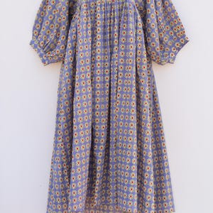 Puede incluir: Un vestido morado con estampado floral. El vestido tiene una cintura fruncida y mangas abullonadas.