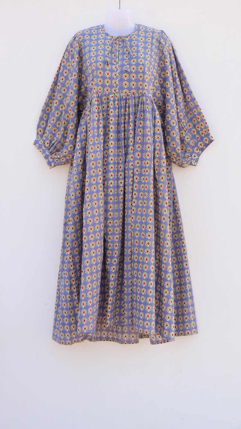 Puede incluir: Un vestido morado con estampado floral. El vestido tiene una cintura fruncida y mangas abullonadas.