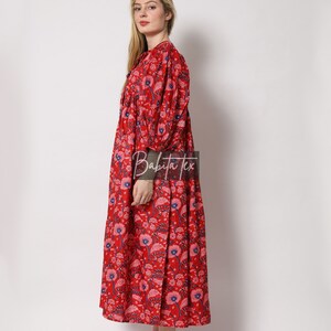 Puede incluir: Un vestido maxi rojo con estampado floral. El vestido tiene un escote en V, mangas largas y una falda fruncida. El vestido est&aacute; hecho de algod&oacute;n y es perfecto para un d&iacute;a de verano.