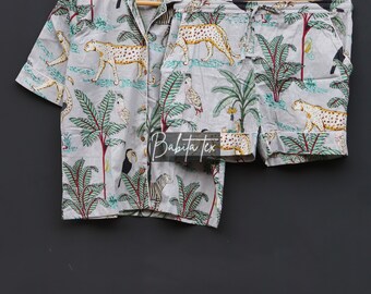 May include: A gray and white pajama set with a tropical print featuring leopards, toucans, and palm trees. The set includes a short-sleeved shirt and matching shorts.