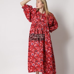 Puede incluir: Un vestido maxi rojo con estampado floral y un lazo en el cuello. El vestido tiene una falda fruncida y mangas abullonadas.