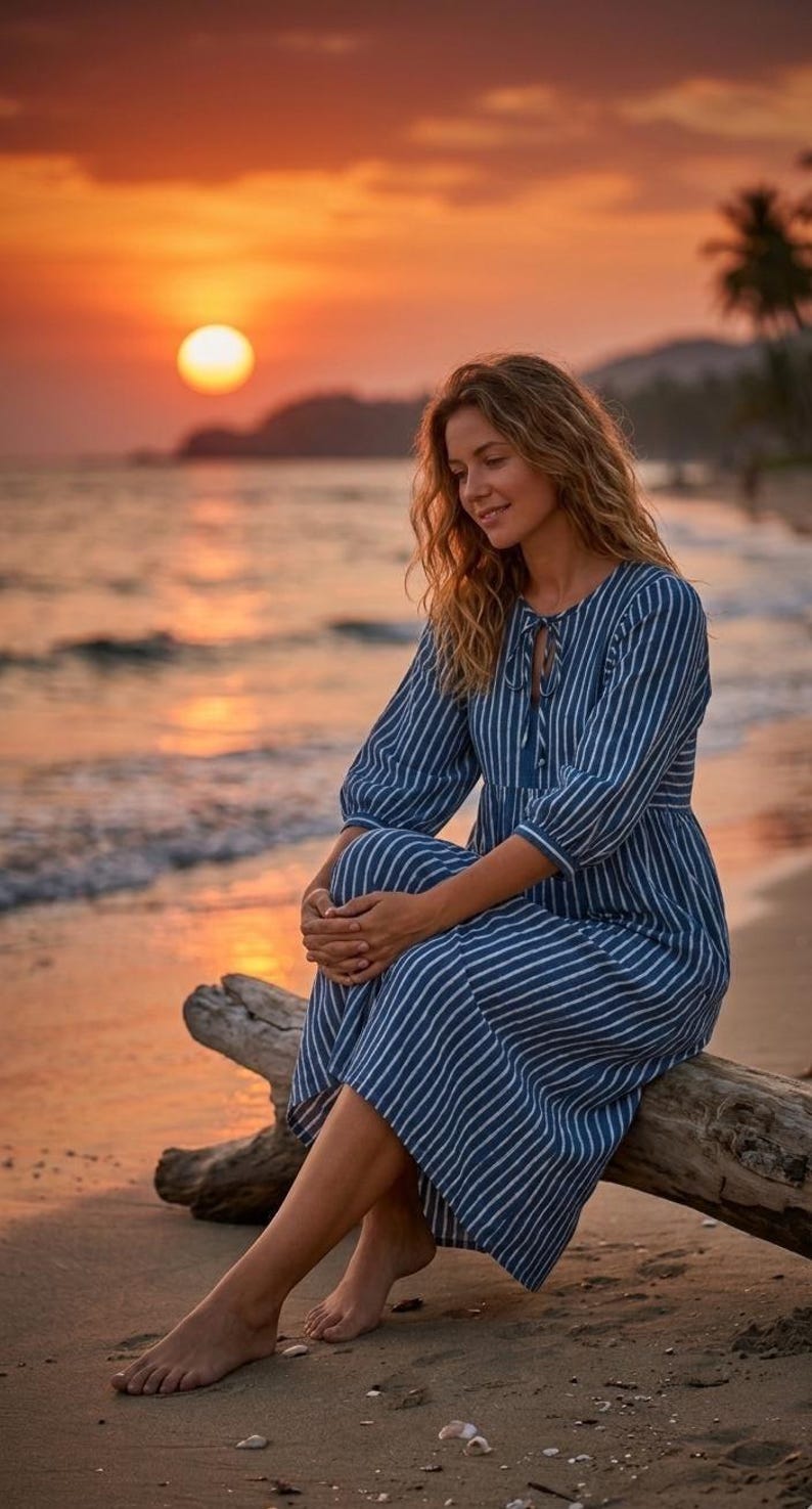 May include: A blue and white striped midi dress featuring three-quarter length sleeves, a gathered waist, and a round neckline with a tie-front closure. The garment is constructed with a tiered skirt design and a relaxed, flowing silhouette.