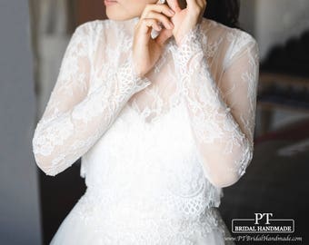 May include: A white long-sleeved lace top featuring a high neckline and intricate floral patterns. The garment has sheer sleeves and a scalloped hemline. The text PT BRIDAL HANDMADE and PTBridalHandmade.com is visible in the bottom right corner.