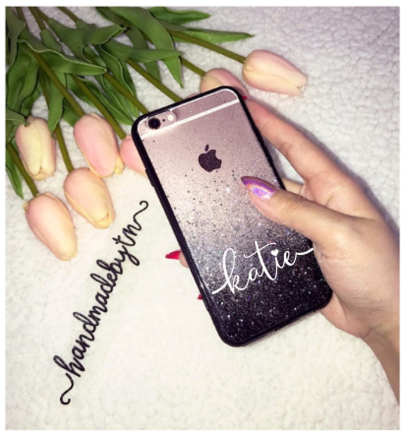 May include: A black and silver glitter phone case with the name "katie" written in white cursive. The case is handmade and has a gradient effect.
