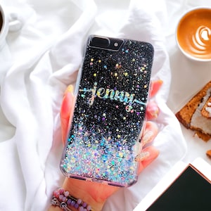 May include: A black glitter phone case with a holographic finish. The case has the name "Jenny" written in gold glitter on the back.