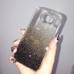 May include: A clear phone case with a black and gold glitter gradient. The glitter is loose and moves around inside the case.