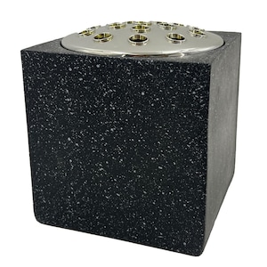 May include: A black square-shaped ceramic vase with a silver metal top and multiple holes for flowers. The vase has a speckled finish.