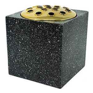 May include: A square ceramic vase with a speckled black and white finish. It has a gold metal top with multiple holes for flower stems.