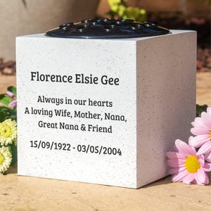May include: White concrete memorial vase with a black plastic insert for flowers. The vase has an inscription that reads "Florence Elsie Gee Always in our hearts A loving Wife, Mother, Nana, Great Nana & Friend 15/09/1922 - 03/05/2004".