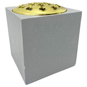 May include: A square grey concrete flower vase with a gold metal top and multiple holes for flower stems.